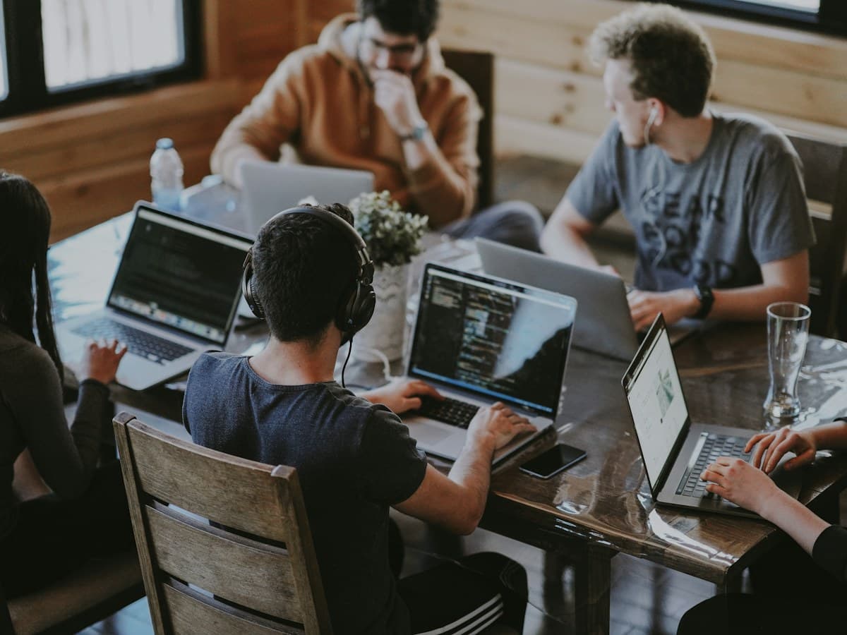 Design team collaborating around laptops in a modern creative office