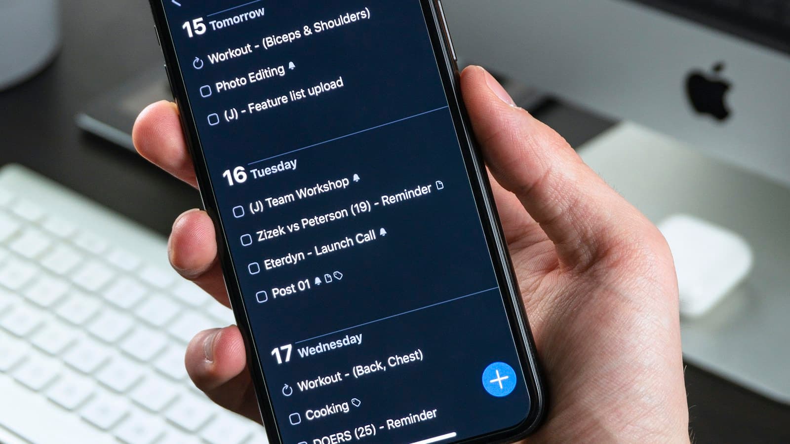 Person holding a smartphone while checking reminders and a daily calendar