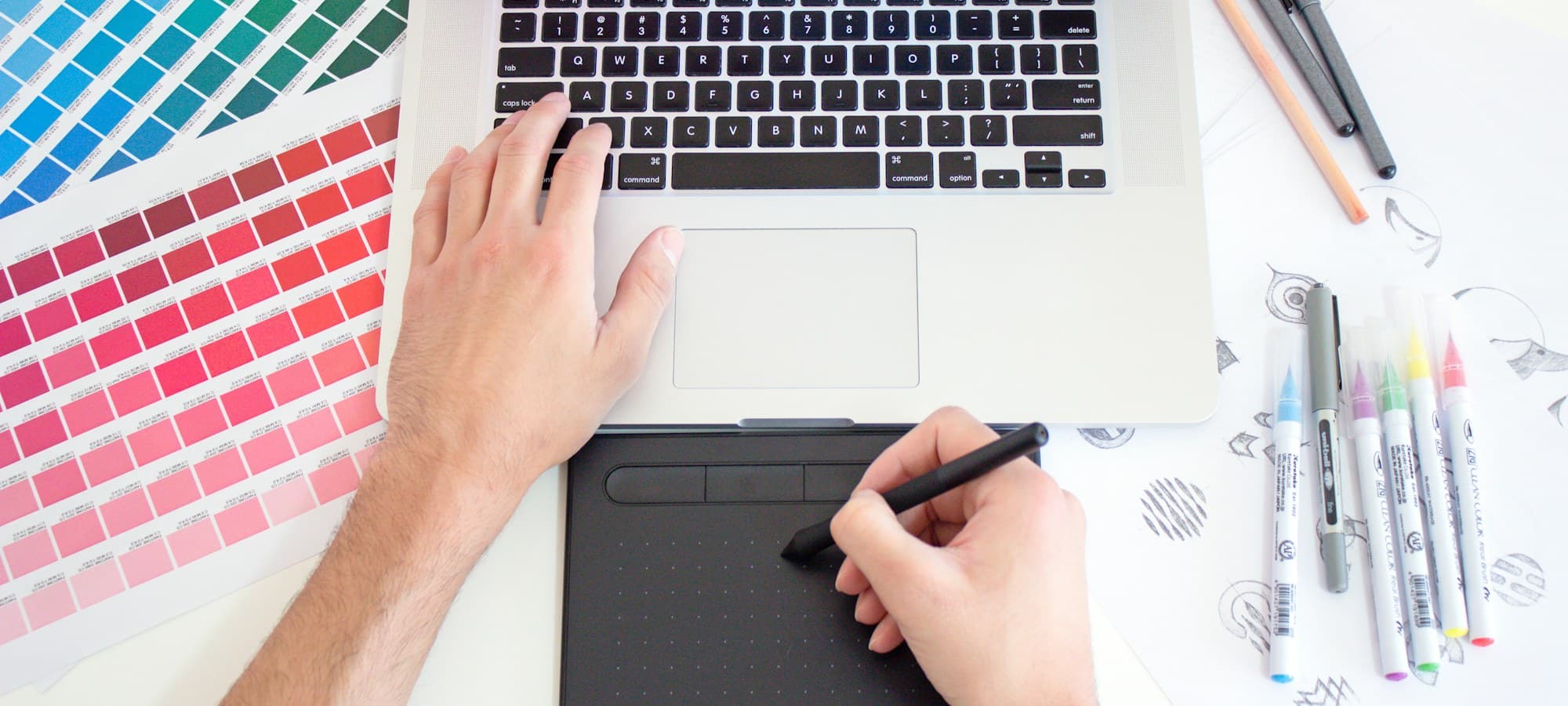 Designer's process workspace with digital tablet, laptop and colour swatches